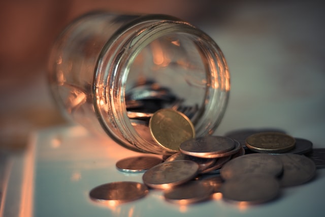 clear glass jar with coins pouring out of it