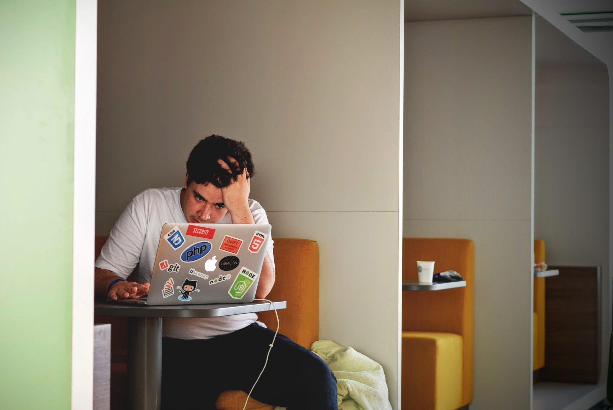 young man wearing a white t-shirt while using a macbook laptop